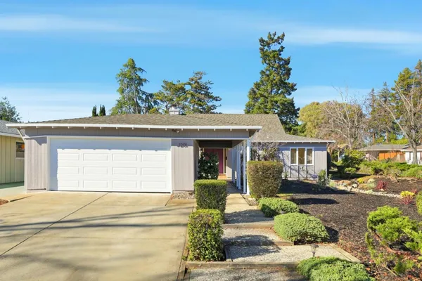 a front view of a house with a yard and potted plants