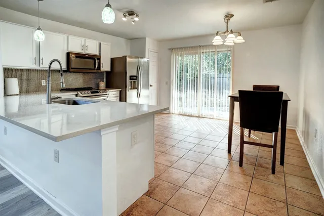 a kitchen with stainless steel appliances a stove a sink a microwave a refrigerator and chairs