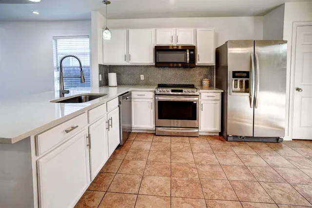 a kitchen with stainless steel appliances granite countertop a refrigerator a stove a sink and a microwave