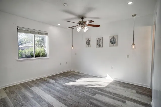 an empty room with a window and ceiling fan