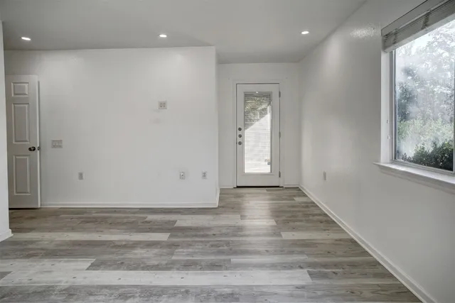 a view of an empty room with wooden floor and a window