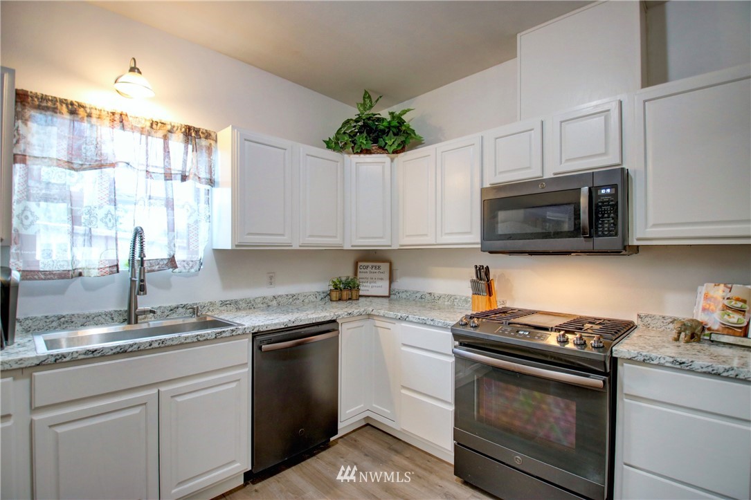 910 Cook Road Sedro-Woolley, WA 98284 - Photo 11 of 37 a kitchen with granite countertop white cabinets appliances a sink and a window