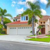 a front view of a house with a garden and trees