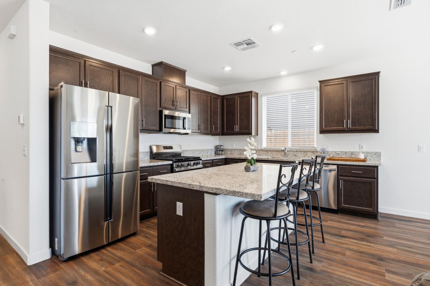 5713 Natalie Way Keyes, CA 95328 - Photo 3 of 30 a kitchen with stainless steel appliances granite countertop a refrigerator a stove a sink a dining table and chairs