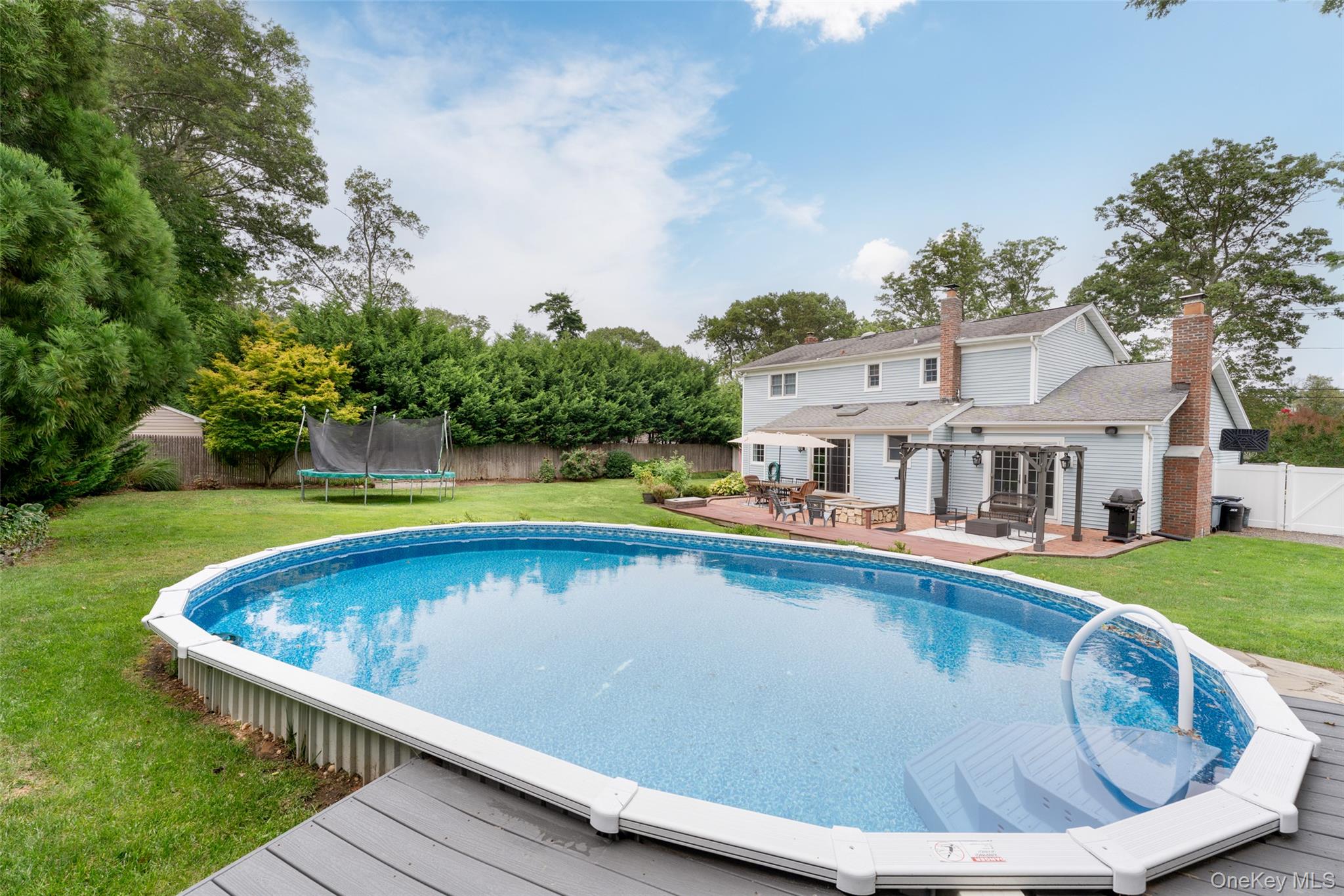 8 Miller Avenue Shoreham, NY 11786 - Photo 29 of 36 a view of swimming pool with outdoor seating and trees in the background