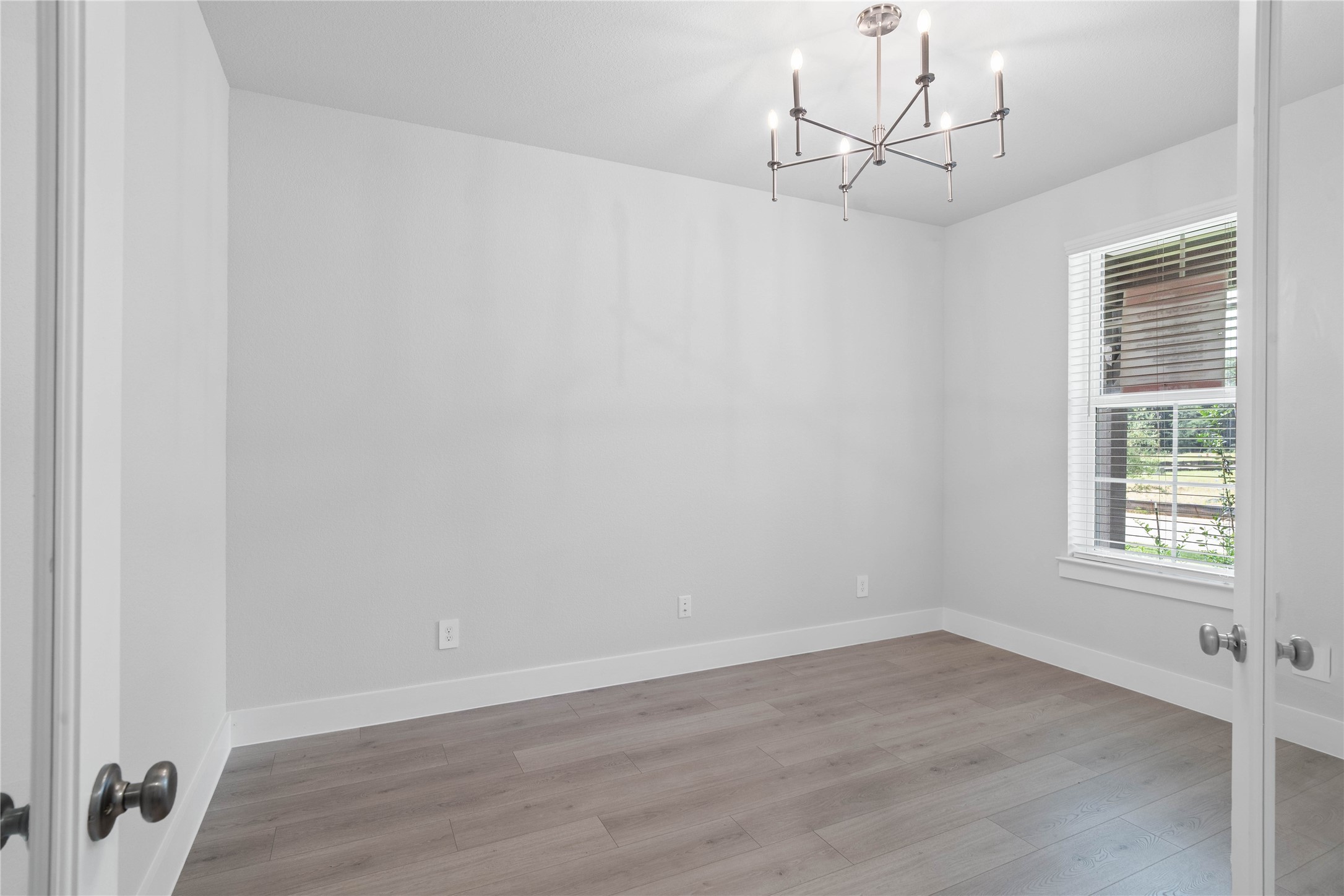 2035 Frst Strm Way Conroe, TX 77304 - Photo 8 of 45 Tucked peacefully at the front of the home is the study. It offers a bright and airy atmosphere with high ceilings, gorgeous chancelier, neutral walls, laminate flooring, French doors, and a large window that fills the space with natural light.