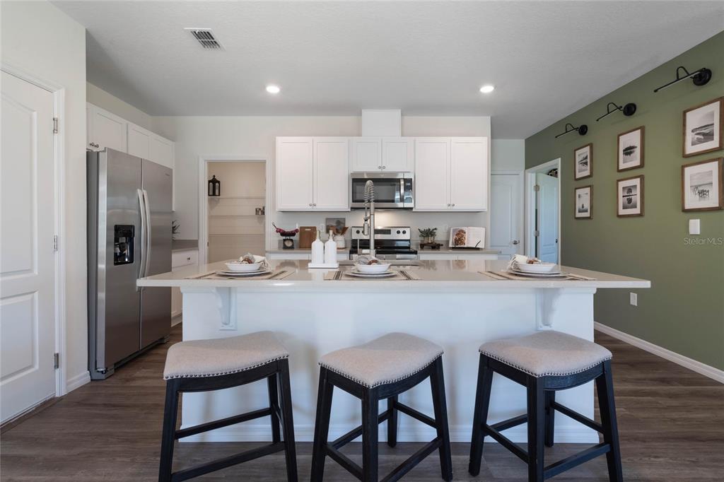 3427 Nettle Loop Tavares, FL 32778 - Photo 10 of 29 a kitchen with stainless steel appliances granite countertop a dining table chairs refrigerator and cabinets