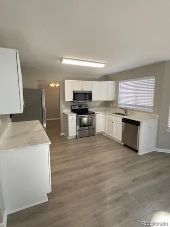 a kitchen with stainless steel appliances wooden floor and a refrigerator