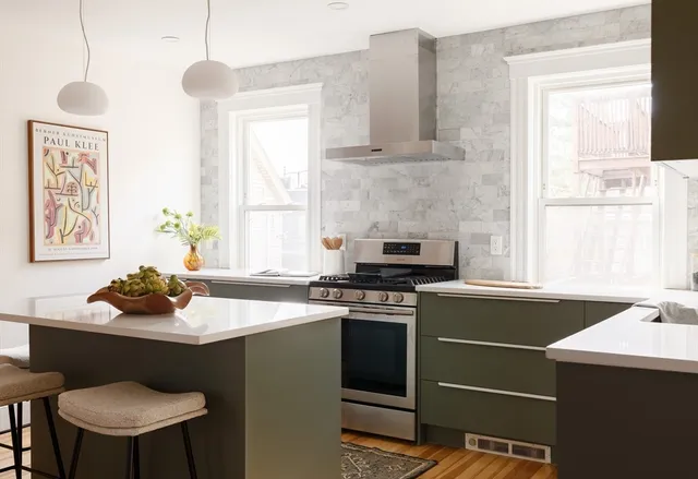 a kitchen with a stove a sink cabinets and a window