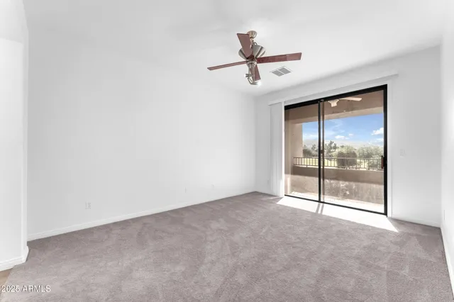 an empty room with windows and fan