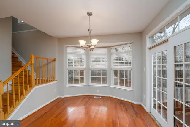 a view of an empty room with wooden floor and windows