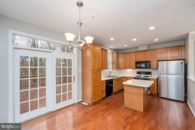 a kitchen with stainless steel appliances granite countertop a refrigerator a stove top oven a sink dishwasher and a refrigerator with wooden floor