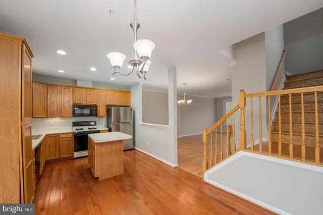 a kitchen with stainless steel appliances kitchen island granite countertop a refrigerator a stove a microwave oven a sink with island and chairs