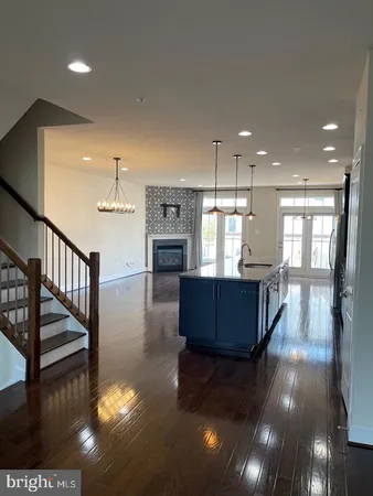 a living room with hard wood flooring and a kitchen