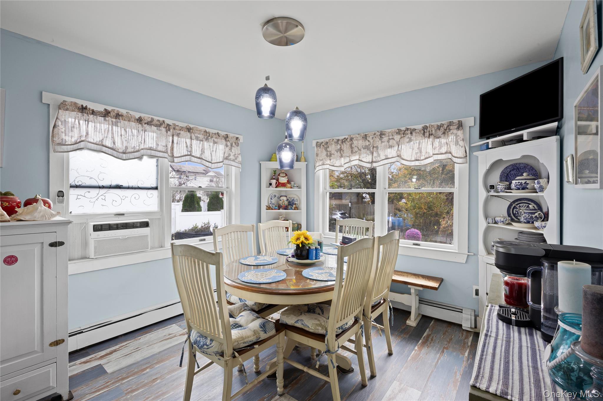 1 Elm Road East Mastic Beach, NY 11951 - Photo 16 of 28 a dining room with furniture a flat screen tv and a floor to ceiling window