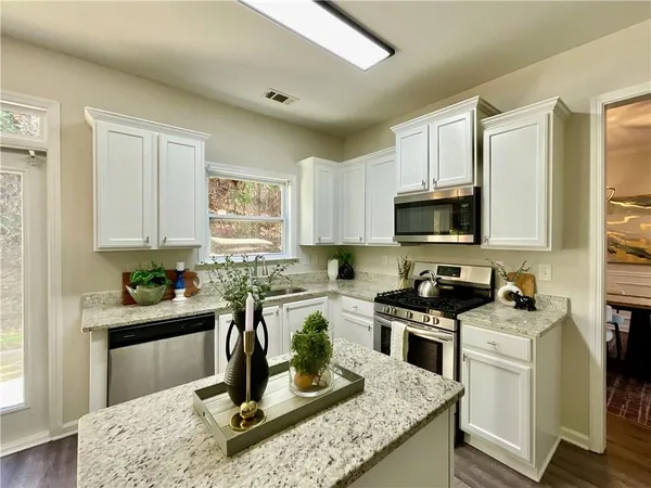 a kitchen with granite countertop a sink stainless steel appliances and cabinets