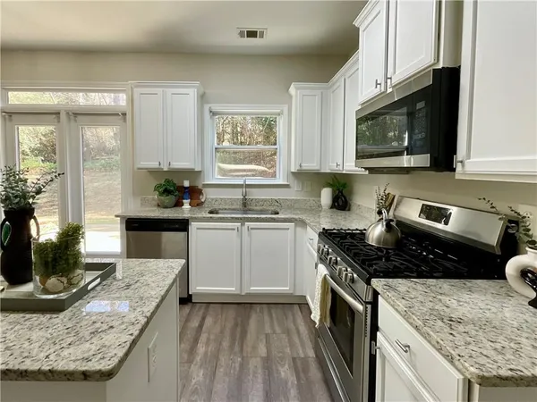 a kitchen with granite countertop stainless steel appliances a stove sink and cabinets