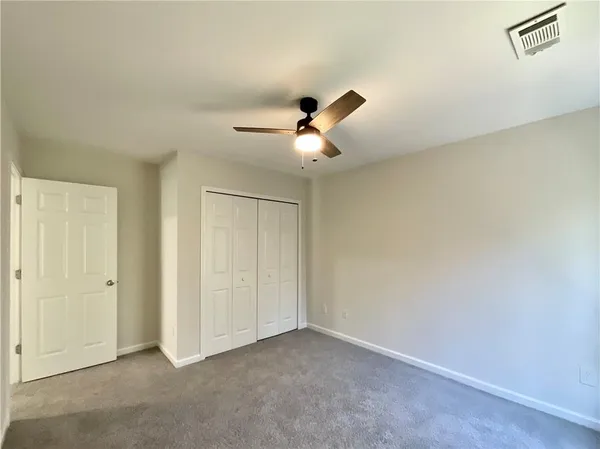an empty room with closet and ceiling fan