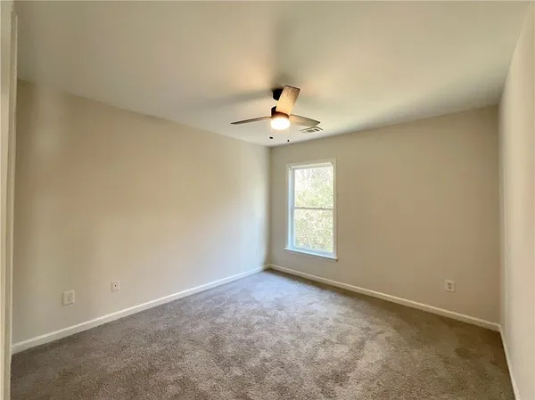 an empty room with windows and chandelier fan