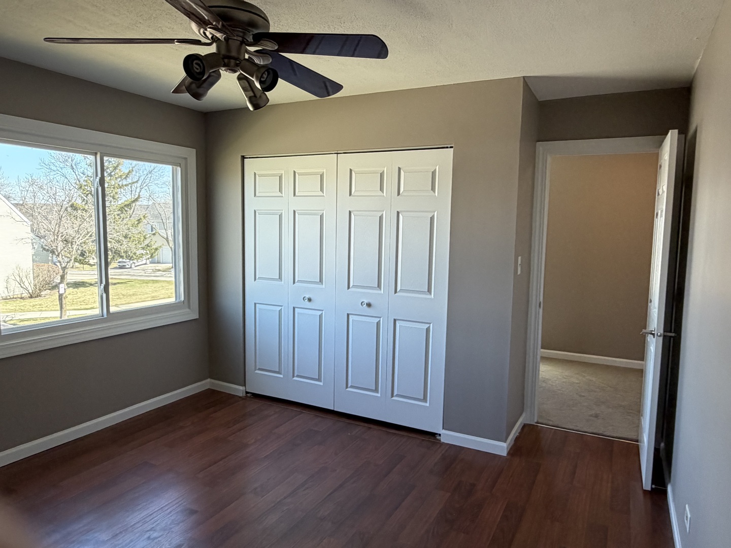 7594 Sarson Way Hanover Park, IL 60133 - Photo 12 of 26 an empty room with wooden floor fan and windows