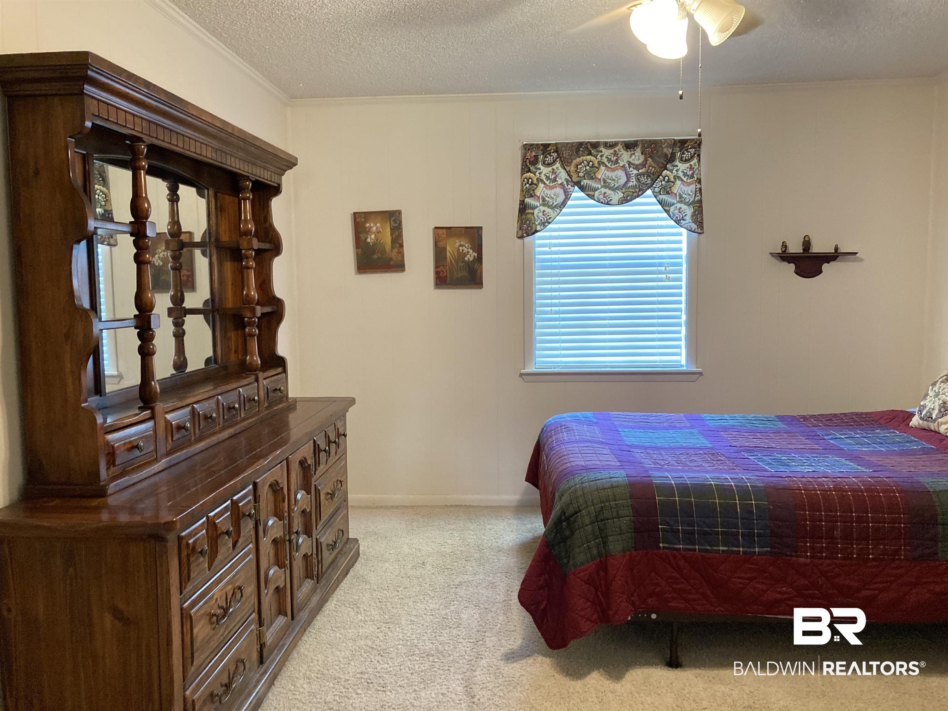 6151 Meadows Road Walnut Hill, FL 32568 - Photo 14 of 29 Bedroom with ceiling fan, light colored carpet, and a textured ceiling