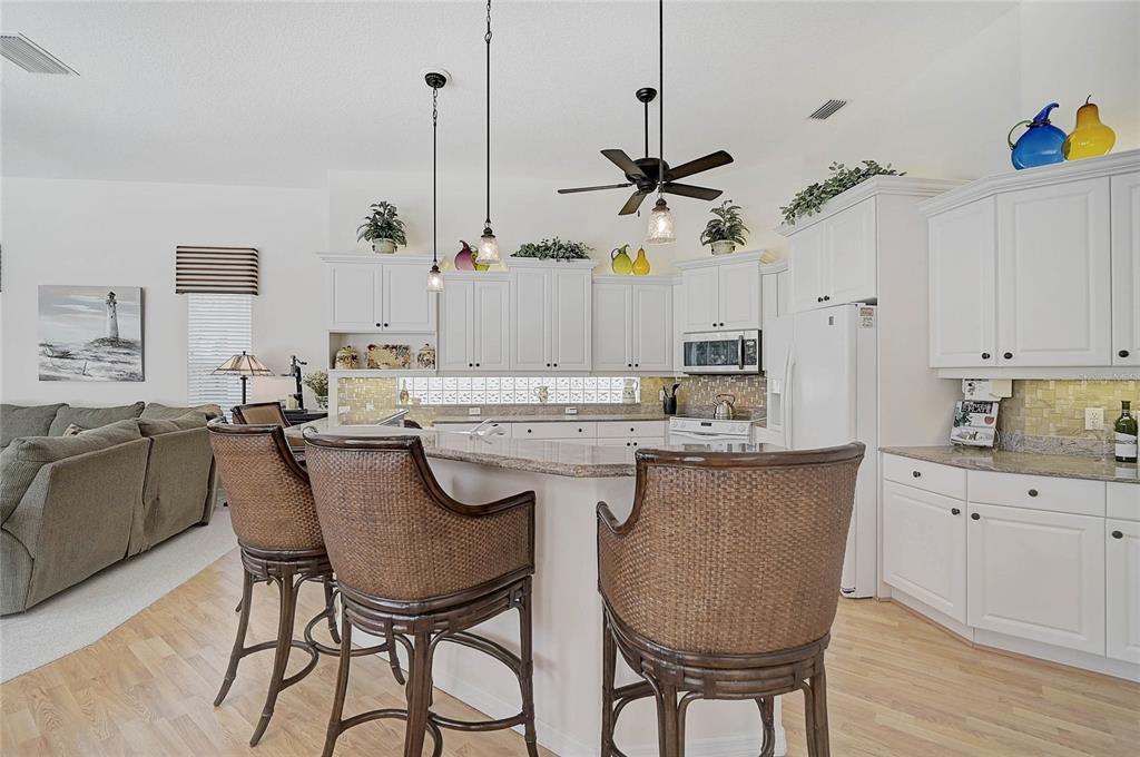2111 Muskogee Trail Nokomis, FL 34275 - Photo 25 of 58 a kitchen with stainless steel appliances granite countertop a sink a stove a dining table and chairs with wooden floor