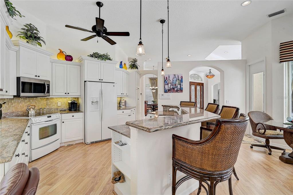 2111 Muskogee Trail Nokomis, FL 34275 - Photo 28 of 58 a kitchen with stainless steel appliances kitchen island granite countertop a stove a sink dishwasher a dining table and chairs with wooden floor