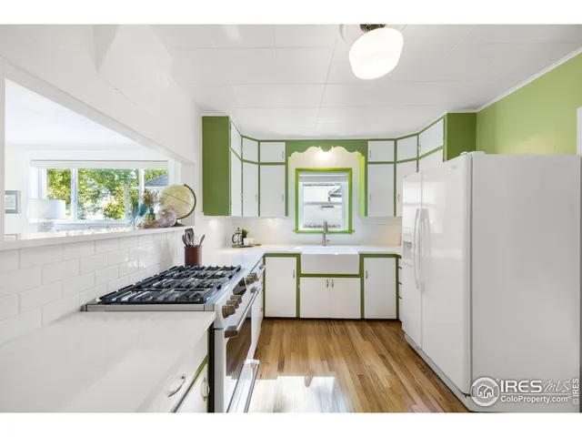 a kitchen with a refrigerator a stove a sink dishwasher with a dining table and chair with wooden floor