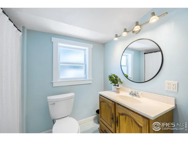 a bathroom with a toilet sink mirror and vanity