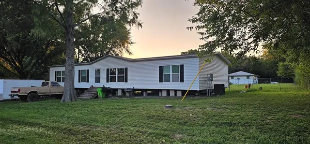 a front view of a house with a garden and trees