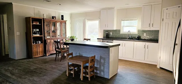 a kitchen with stainless steel appliances granite countertop a stove a refrigerator a sink a dining table and chairs with wooden floor