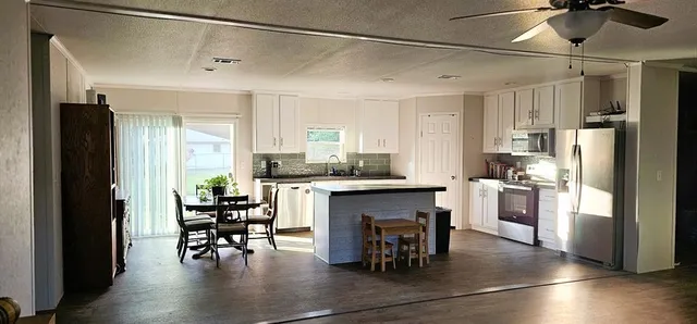 a kitchen with granite countertop a refrigerator a stove a dining table and chairs with wooden floor