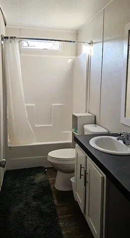 a bathroom with a granite countertop sink toilet and shower