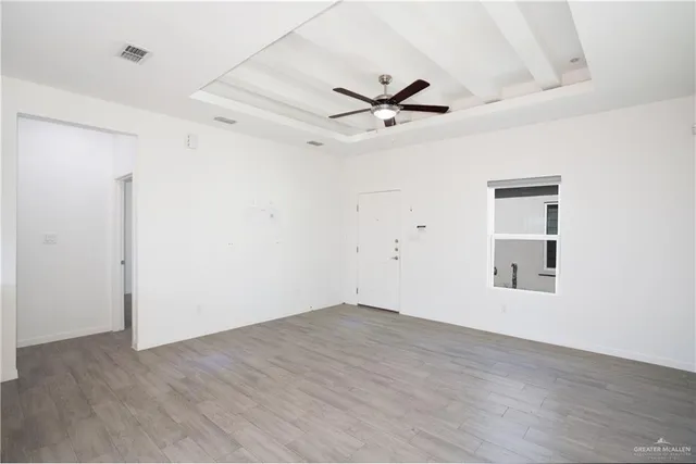 a view of empty room with wooden floor and fan