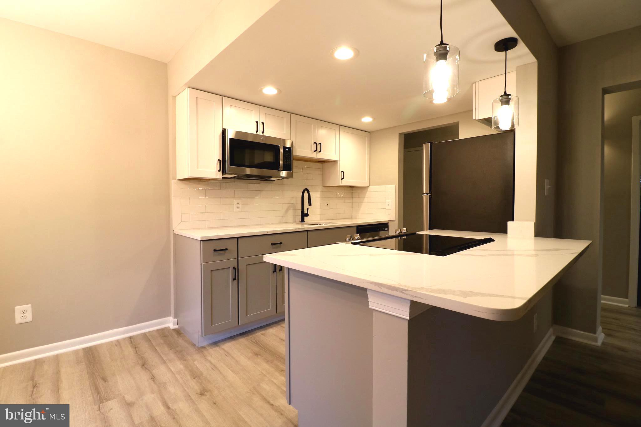 2249 Castle Rock Square, Unit 11C Reston, VA 20191 - Photo 4 of 26 a kitchen with a sink a microwave a refrigerator and cabinets