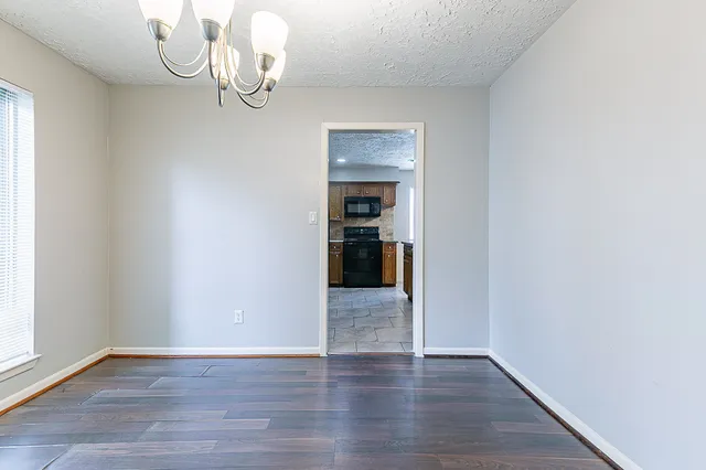 a view of an empty room with wooden floor and windows
