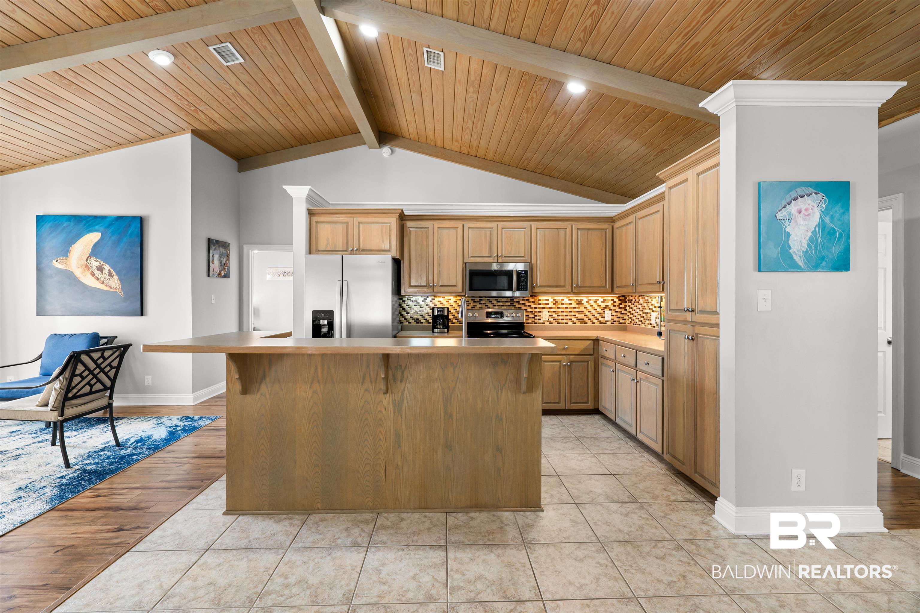 19079 Baldwin County Road 10 Foley, AL 36535 - Photo 29 of 37 Kitchen featuring a wood ceiling with exposed beams, a kitchen island, stainless steel appliances, decorative backsplash, and a breakfast bar area