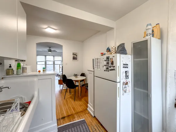a kitchen with stainless steel appliances a refrigerator a stove a dining table and chairs with wooden floor