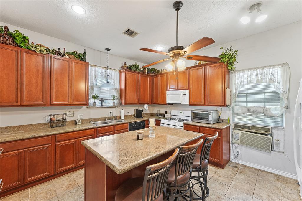 8515 Sandy Hill Road Brenham, TX 77833 - Photo 18 of 25 Kitchen featuring a kitchen breakfast bar, a textured ceiling, decorative light fixtures, light stone counters, and a kitchen island