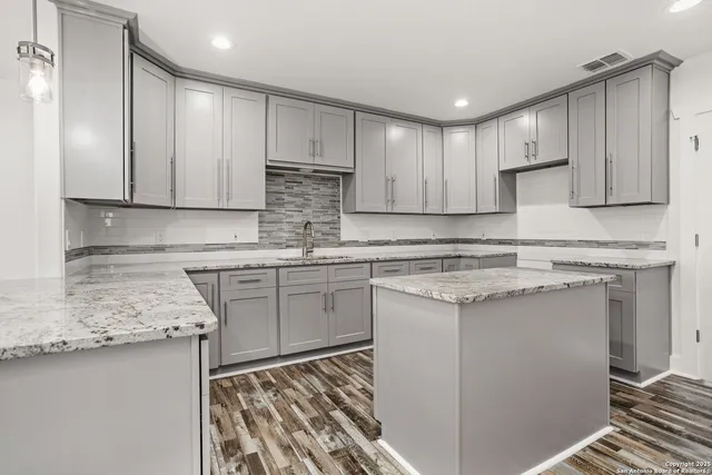 a kitchen with stainless steel appliances granite countertop a sink stove and white cabinets with wooden floor