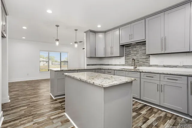 a kitchen with kitchen island granite countertop a sink stove and cabinets