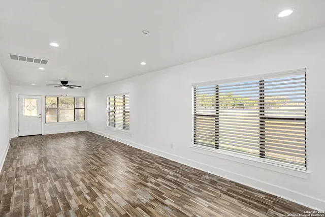 a view of empty room with wooden floor and fan