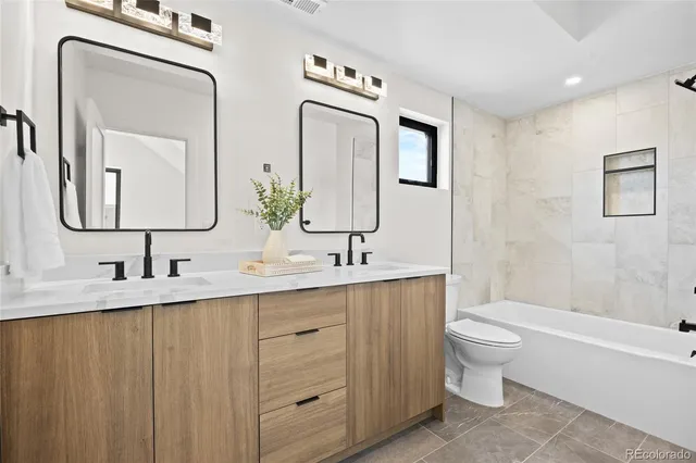 a bathroom with double vanity sinks a toilet and a bathtub