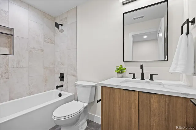a bathroom with a granite countertop toilet a sink and a bathtub