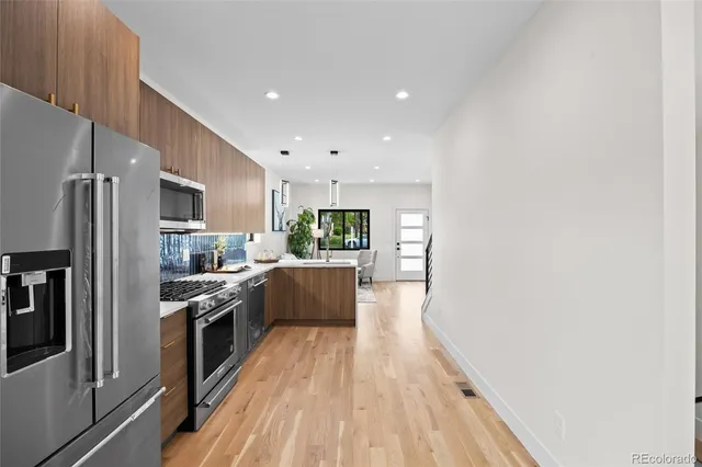 a large kitchen with stainless steel appliances granite countertop a refrigerator a stove a sink dishwasher and a oven with wooden floor