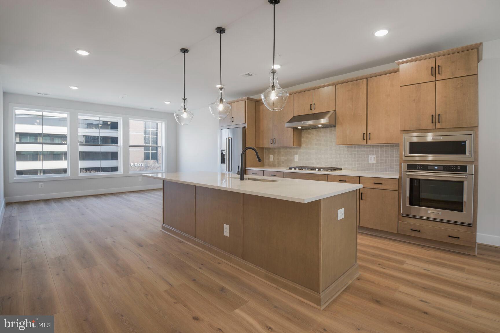 6020 Montrose Road North Bethesda, MD 20852 - Photo 11 of 27 a kitchen with stainless steel appliances granite countertop a stove a sink and a refrigerator with wooden floors