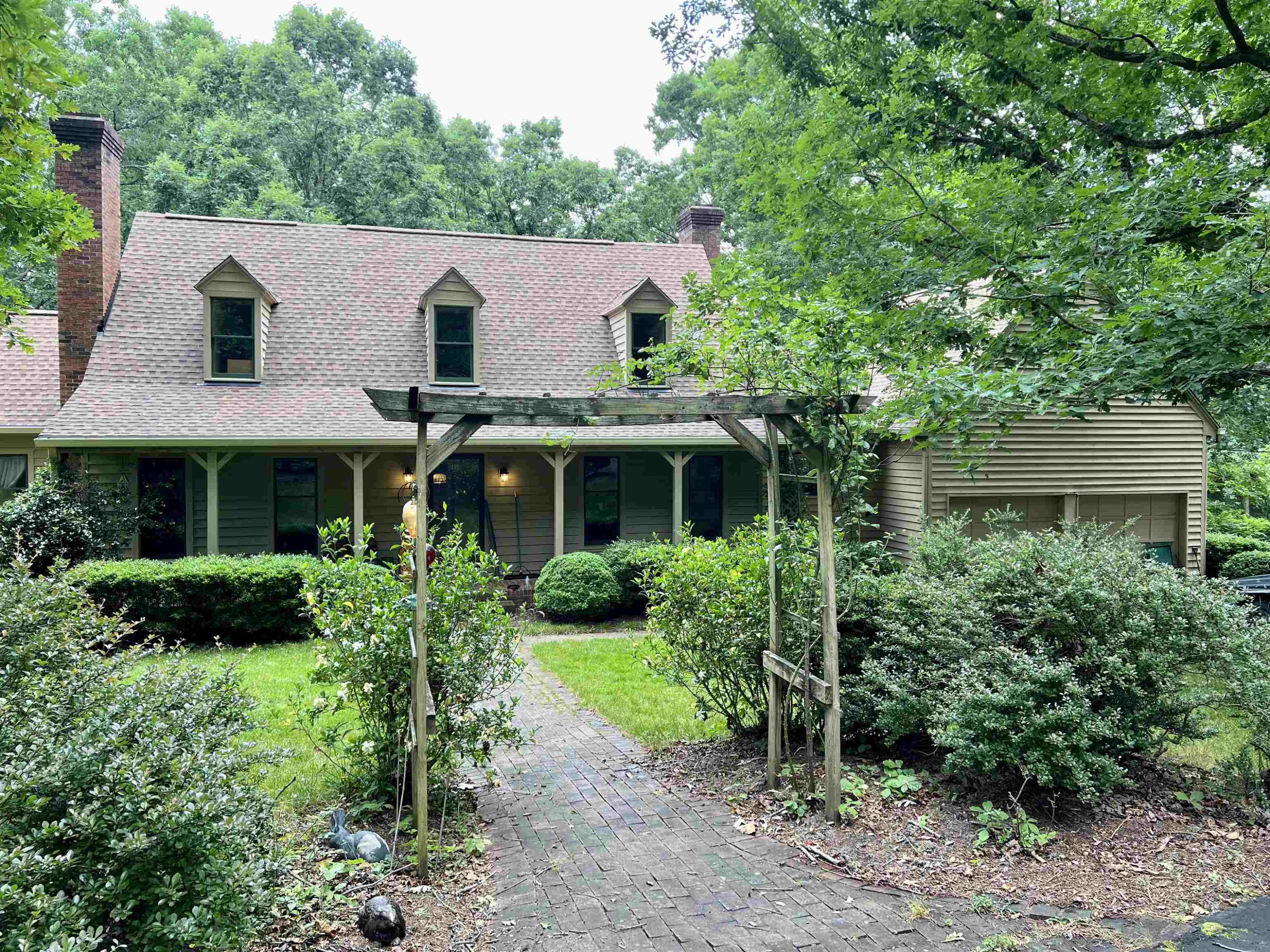 a view of a house with lots of plants and a tree