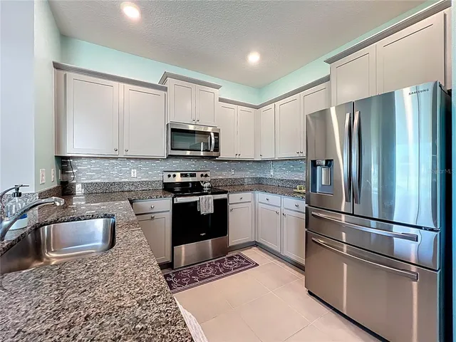 a kitchen with granite countertop a refrigerator stove and sink