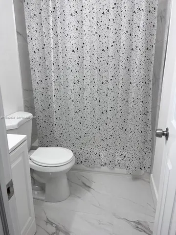 a bathroom with a toilet and a shower curtain
