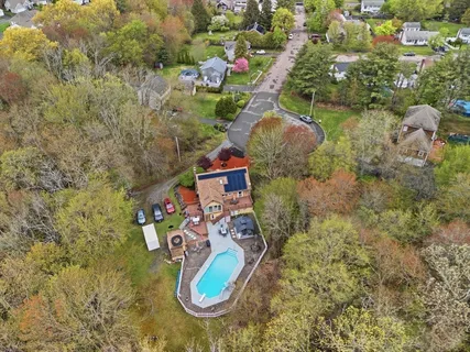 an aerial view of a house with a yard and a large tree
